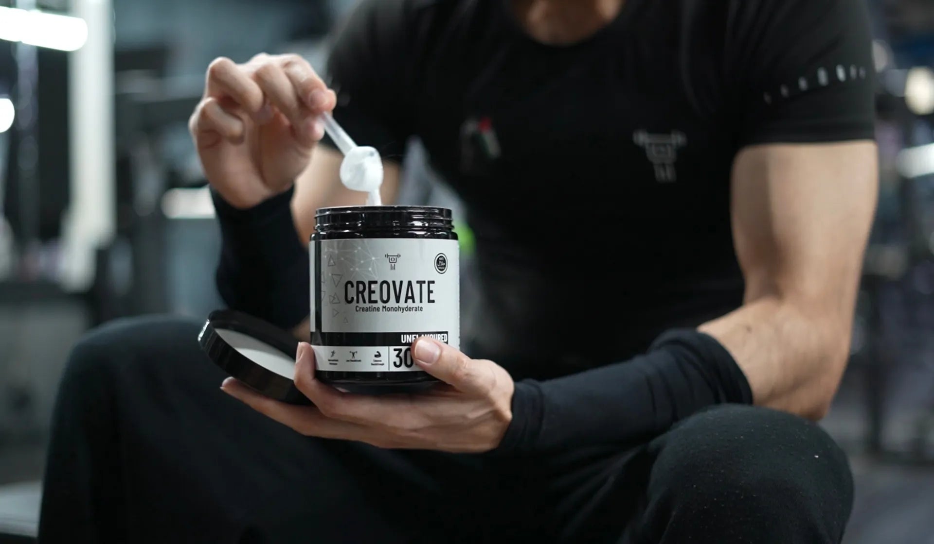 Person holding a container labeled 'Creovate' in a gym setting